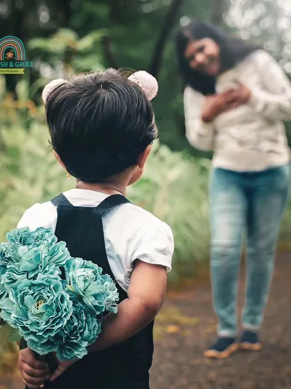 A surprise for mom. This heartwarming shot captures a sweet moment of a child about to give flowers to her mother during their family photoshoot.