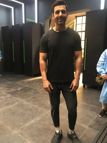 John Abraham on set in a simple, athletic look. Even in a basic black t-shirt and joggers, the right fit is key to looking sharp.