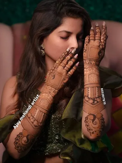 A graceful pose highlighting the intricate patterns on both arms. This design features bold geometric shapes mixed with delicate peacock details, perfect for a modern bride.