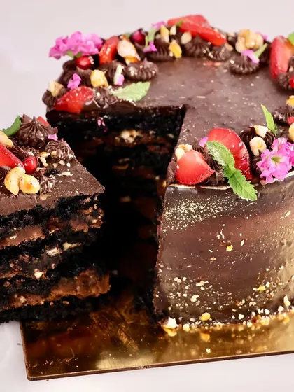 A slice of our vegan, gluten free, and refined sugar free chocolate cake. You can see the rich, moist layers made with millet and almond flour, proving that healthy can be incredibly indulgent.