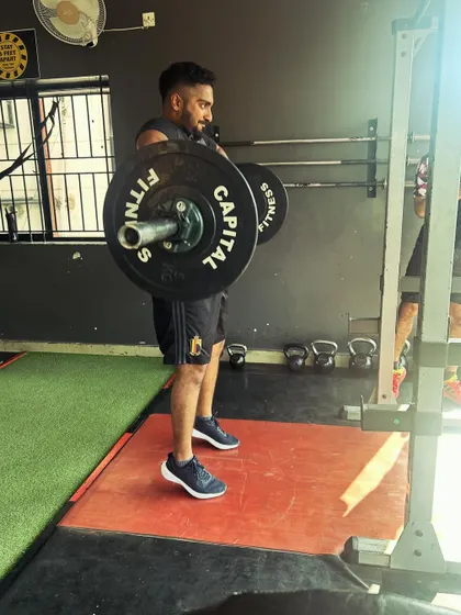 A client holds a heavy barbell at the start of a deadlift, ready to engage his entire body in the lift.
