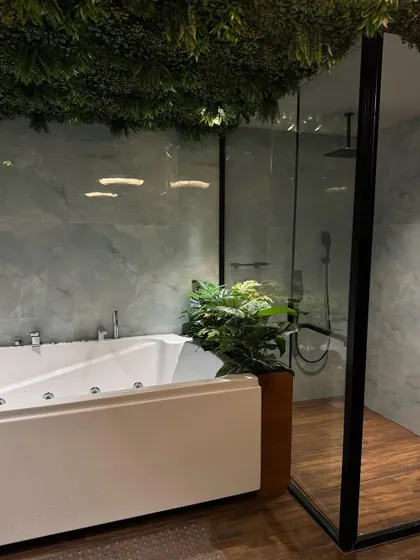 A view of the bathroom featuring the artificial grass ceiling and a large potted plant next to the tub. The combination of green elements creates a cohesive, spa-like atmosphere.