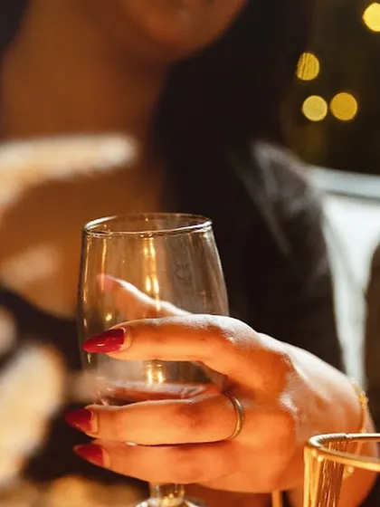 A guest holds a glass of wine, with the soft bokeh of fairy lights in the background. It's these small, beautiful moments that define an evening at Shamiyana.