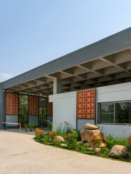 To achieve a column-less large span for the gateway, we used a coffer slab roofing system that adds to the post-industrial character. Panels of brick jaali, Sira stone, and chain-link for creepers create a beautiful play of light and shadow.