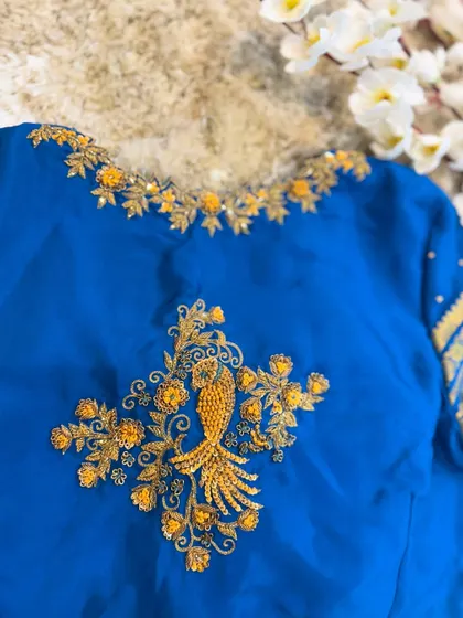 The back of a blue blouse featuring a stunning peacock motif created with intricate zardosi and beadwork.