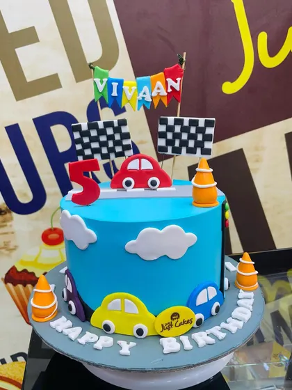 A 2.5kg race car theme cake with a finish line banner and colorful fondant cars.
