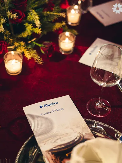 A personalized menu placed on a deep red tablecloth, surrounded by the soft glow of candles. This intimate detail shows our focus on creating a bespoke and thoughtfully curated experience for every guest.