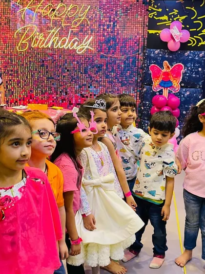 A group of happy kids posing at a pink-themed birthday party. I focus on creating a fun, social atmosphere for all the children.