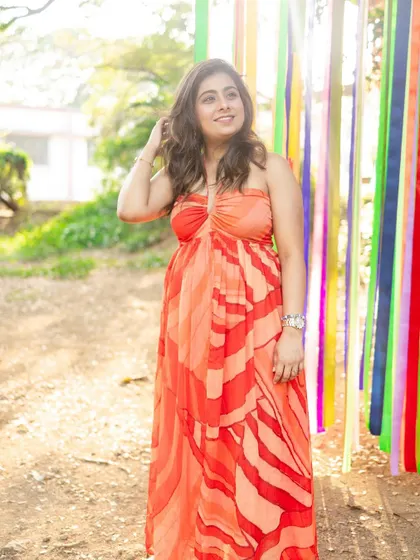 The bride-to-be in a vibrant orange dress. The soft, natural makeup ensures the focus remains on her and the beautiful colors of her outfit and the surroundings.