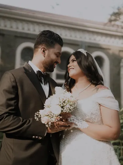 A classic portrait of a Christian wedding couple. The groom looks at his bride with adoration as she holds her bouquet.