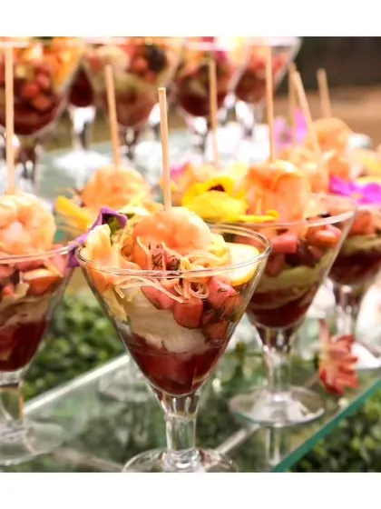 Elegant shrimp cocktail glasses layered with noodles, fresh vegetables, and a succulent prawn, showcasing our ability to create stunning seafood appetizers.