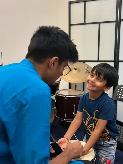 A teacher and a young student share a smile during a djembe lesson. These moments of connection and joy are at the heart of what we do.