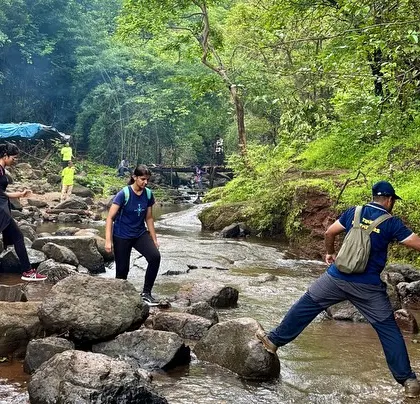 Our guide helping a trekker cross a stream on the way to Devkund. We always ensure our groups move safely.