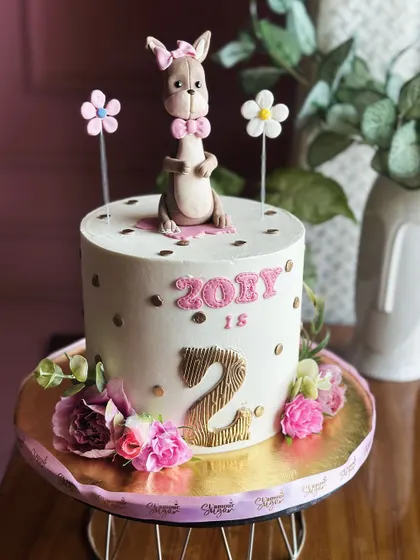 Two sweet to handle! This adorable second birthday cake features a cute kangaroo topper and delicate floral details for a charming and fun celebration.