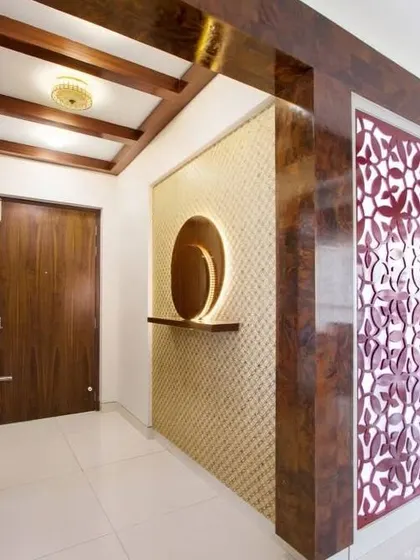 A traditional-meets-modern foyer with rich wood paneling and a decorative jaali screen. The backlit mirror adds a contemporary touch to the warm, classic space.