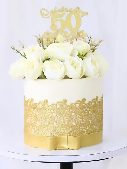 A classic and elegant cake for a 50th birthday. The design combines a beautiful gold lace wrap with a bouquet of fresh white roses, creating a timeless look for a golden jubilee.