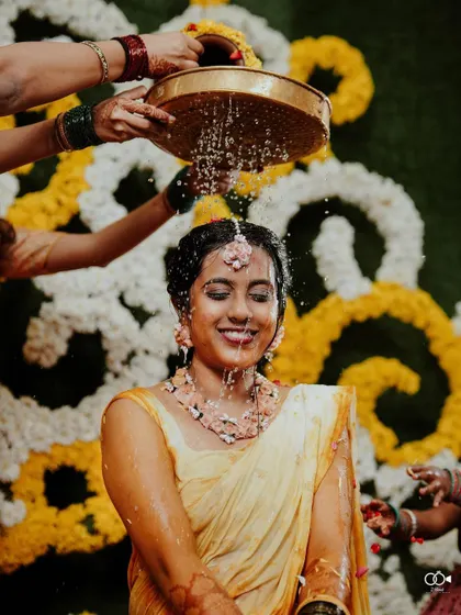 A beautiful, happy shot of the bride during the water-pouring ritual of her Haldi ceremony.