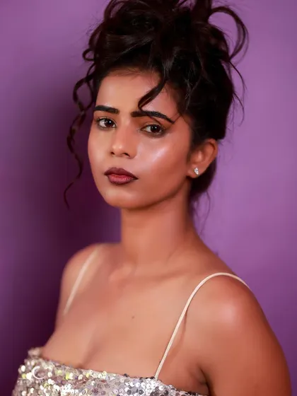 A striking close-up portrait in a silver sequin dress. The messy updo and bold lip create a look that is both glamorous and edgy.