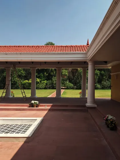 This upcoming farmhouse project showcases a fusion of modern architectural lines with traditional Indian materials. The colonnaded veranda creates a shaded transitional space, overlooking the grounds and connecting the home to its rustic setting.