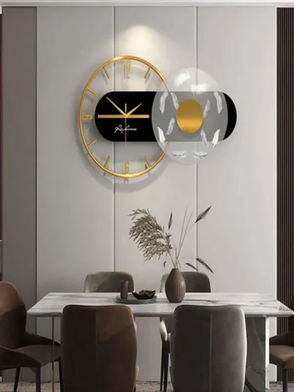 This imported wall clock showcases a horizontal design with a transparent, feather-detailed element. The mix of black, gold, and clear acrylic creates a light, airy, and thoroughly modern piece of wall decor.