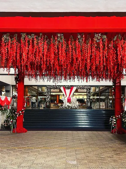 A grand entrance decorated with hanging red flowers for a large-scale celebration.
