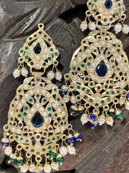 These Rajwadi-style earrings feature beautiful blue and green enamel work, known as meenakari, surrounded by pearls. They are designed to bring a touch of traditional Rajasthani grandeur to any bridal look.