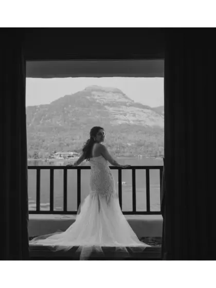 A dramatic black and white silhouette of the bride on the balcony, her gown flowing behind her. The majestic mountain view adds to the epic, cinematic feel of this portrait.