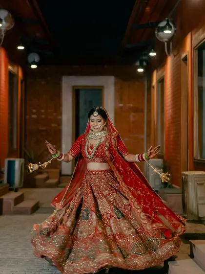 A bride's joyful twirl in a beautifully lit corridor. This dynamic shot captures her happiness and the stunning detail of her wedding lehenga.