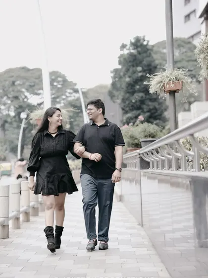 A full-length shot of a couple walking arm-in-arm down a city sidewalk, capturing a simple, happy moment.