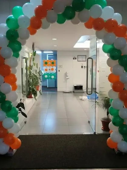 A balloon arch in the colors of the Indian flag (saffron, white, and green) for an Independence Day or Republic Day celebration at an office.
