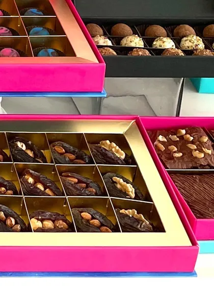 Here you can see some of my most popular Diwali offerings side by side. I have boxes of gourmet nut stuffed dates, assorted brownies, and handmade chocolate truffles, each ready for gifting.