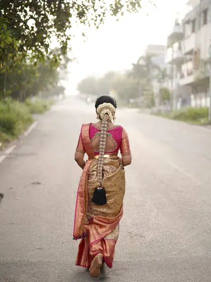 A beautiful shot capturing the bride from behind, showcasing her traditional long braid adorned with flowers as she walks. This highlights the importance of a complete head-to-toe look.