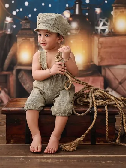 A little sailor surrounded by glowing lanterns. This nautical theme uses warm lighting and rustic props to create a cozy, seafaring vibe.