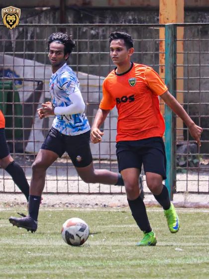 A throwback to an MFA First Division match, showing a player on the ball with determination.