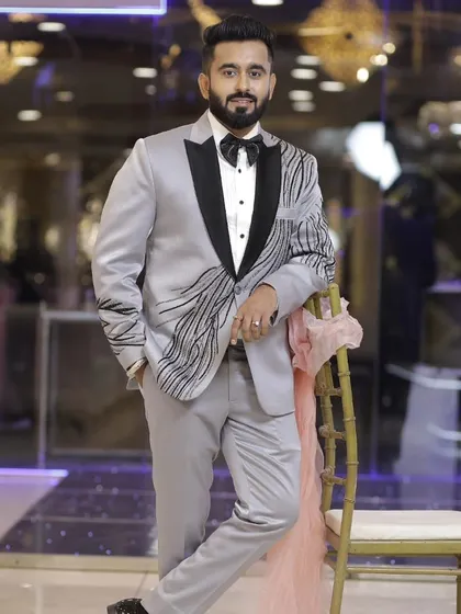 A customer looking sharp and confident in our silver-grey tuxedo. The jacket has a unique black embroidered pattern, making it a modern and stylish choice for any party.