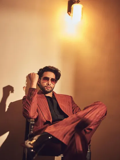 This shot of Siddhant captures the full effect of the pinstripe suit. The warm lighting and relaxed pose give it a cool, cinematic quality.