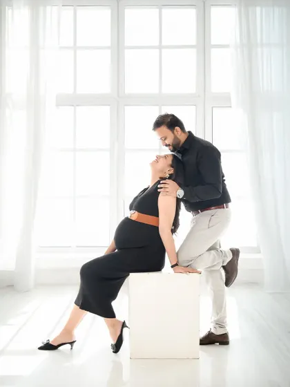 A modern and chic couple's portrait in our minimalist window-lit studio. The black outfits create a striking contrast against the bright white background.