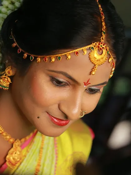 A gentle and serene portrait of a bride, looking down, highlighting her traditional makeup and jewelry.