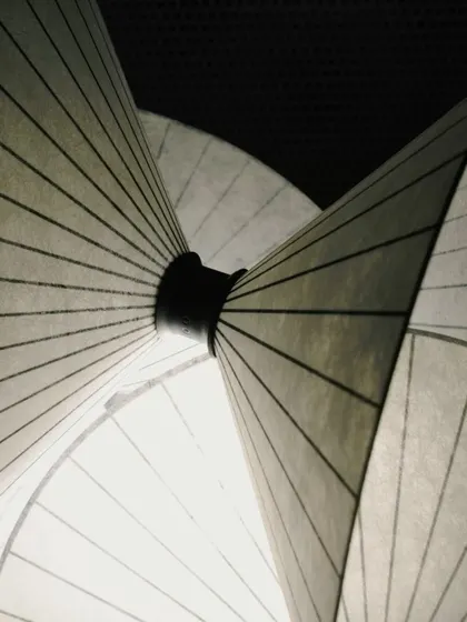 A detailed macro shot of the Serpentine Light, focusing on the point where the paper-like cones converge, revealing the thoughtful construction of the piece.