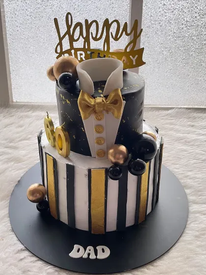 A two-tier tuxedo cake for a dad's 60th birthday. The black and white stripes, gold accents, and bow tie create a very sharp and stylish look.