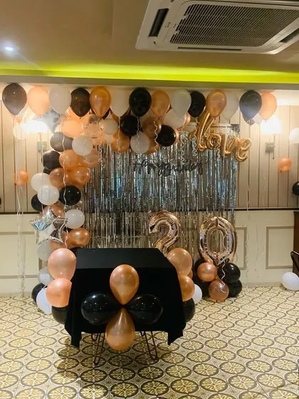 This wide shot shows the full 20th birthday party setup in the event space. I covered the cake table with a black cloth and placed balloons underneath to tie the whole look together.