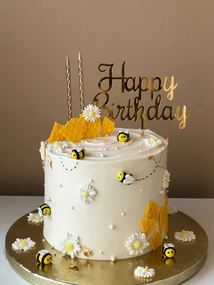 A "bee-autiful" cake with honeycomb details, daisies, and cute fondant bees.