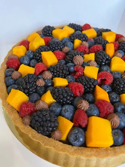 A closer look at my Chocolate Tart with Fresh Mango and Berries. The buttery biscuit base holds a luscious dark chocolate pudding, topped with a vibrant mix of fruit.