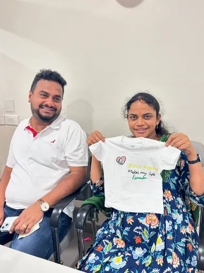 A happy couple with the custom-painted baby t-shirt they made during their baby shower celebration.