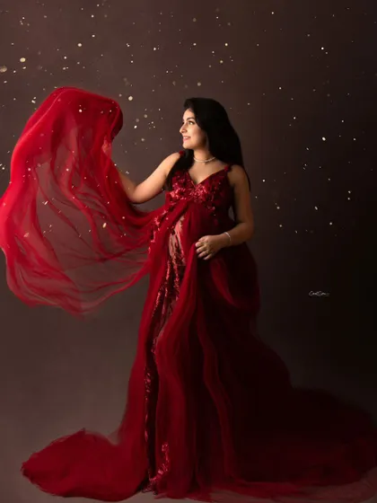 A touch of magic for a radiant mama. This portrait captures her in a brilliant red gown, with the fabric tossed for a dynamic effect and accented with a sprinkle of gold.