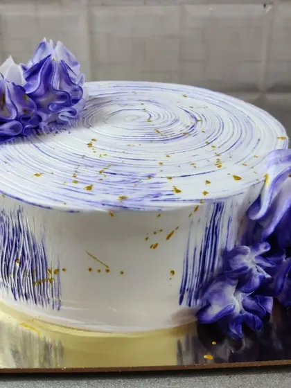 A white cake with a modern, abstract purple watercolor effect and gold flecks. A simple design that makes a big impact.