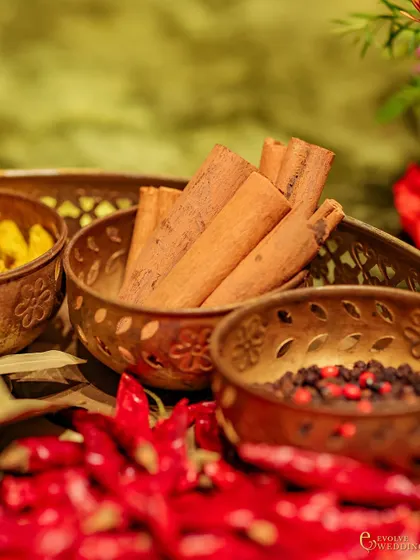 A detail shot of the traditional spices used in the decor: cinnamon sticks, turmeric, peppercorns, and dried red chillies. These elements are not just decorative but are rooted in timeless aesthetics of abundance and protection.