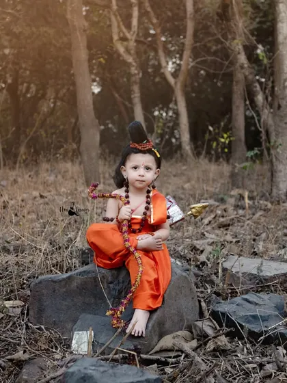 A powerful portrait of a young boy as Lord Ram, sitting thoughtfully in a forest setting. This outdoor shoot brings a different, more natural feel to our cultural themes.