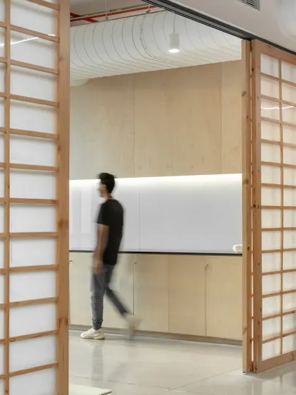 Sliding shoji-inspired screens made of light wood add a layer of warmth and texture to this office space. This element allows for flexible division of space while maintaining a connection to natural materials and minimalist design principles.
