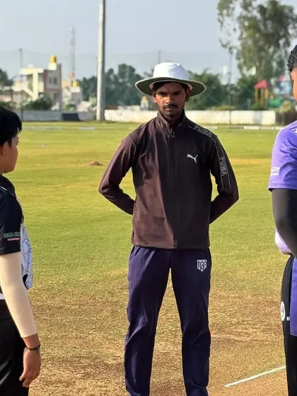 A coach observes the two captains before a league match, ensuring the proceedings are conducted professionally.